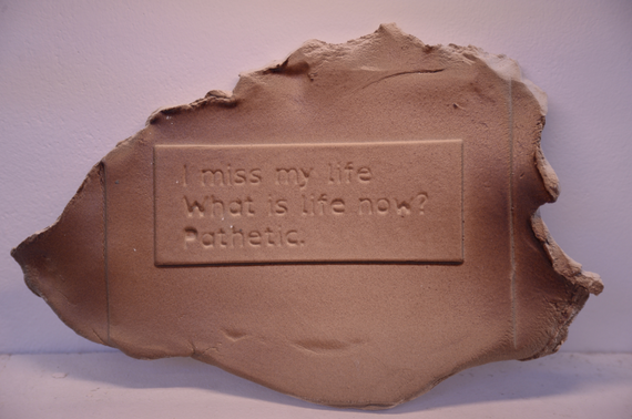 A clay block that says "I miss my life. What is life now? pathetic."